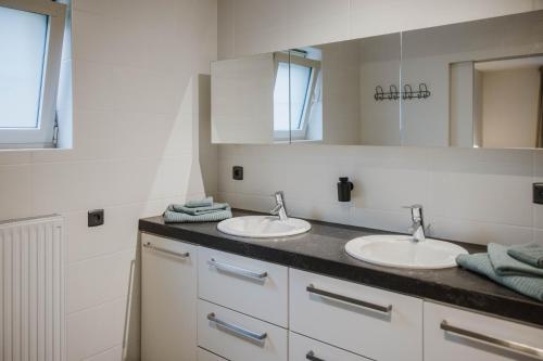 a bathroom with two sinks and a mirror at Vakantiehuis sINNE in Oostmalle