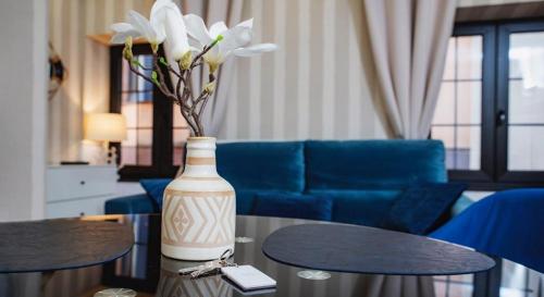 a vase with flowers on a table in a living room at "Breeze" Aparthotel by Parrot`s House in Lloret de Mar