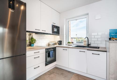 eine Küche mit weißen Schränken und einem Kühlschrank aus Edelstahl in der Unterkunft Rent like home - Browary Wrocławskie in Breslau
