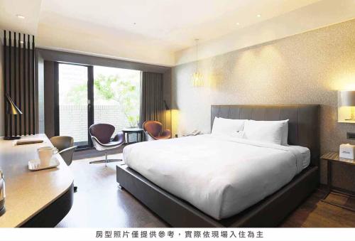 a bedroom with a large white bed and a desk at Royal Group Hotel Minghua Branch in Kaohsiung