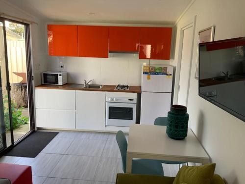a small kitchen with red cabinets and a table and a tableablish at Jetty Road Granny Flat in Normanville