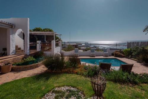 um quintal com piscina e cadeiras e o oceano em Saxon Lodge em Gansbaai