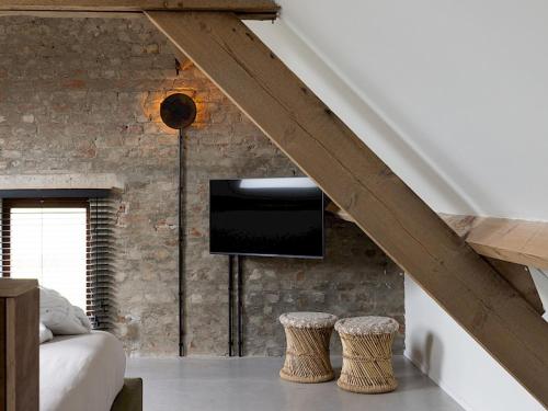 a bedroom with a wall with a television and stools at BBruT in Bruges