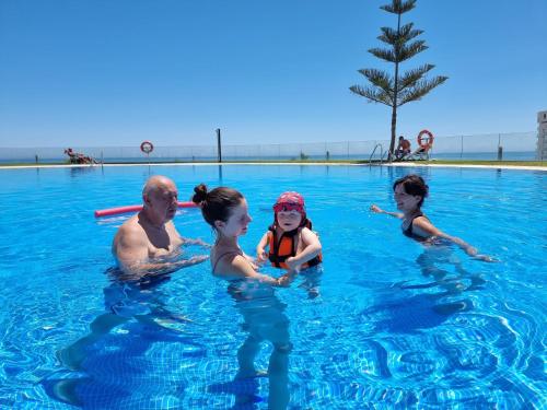 een groep mensen in een zwembad bij Summer House duplex en la playa con piscina in Benalmádena