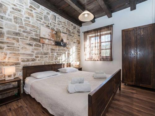 ein Schlafzimmer mit einem großen Bett und einer Steinmauer in der Unterkunft Stone Villa Petit Rustica with pool in Sukošan