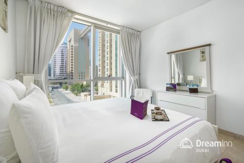 a bedroom with a large white bed with a large window at Dream Inn Apartments- Emaar Towers - Rega Al Buteen in Dubai