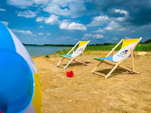 dwa leżaki plażowe siedzące na plaży obok wody w obiekcie Prosportówek - Powidz - Dom Bliźniak nad Jeziorem z Dużym Ogrodem w Powidzu