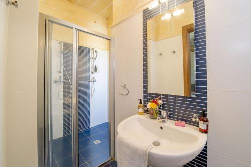 a bathroom with a sink and a shower with a mirror at Hanini Holiday Home in Qala