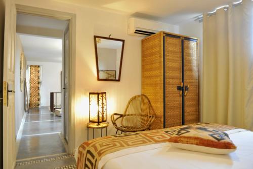 1 dormitorio con cama, espejo y silla en Riad Home Zemrane, en Marrakech