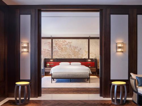 a bedroom with a bed and two stools at Andaz Xiamen, By Hyatt in Xiamen