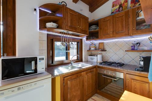 a kitchen with wooden cabinets and a sink and a microwave at Samarighouse in Putzu Idu