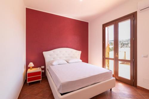 a bedroom with a white bed and a red wall at Appartamento Custonaci Uno in Custonaci
