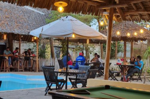 people sitting at tables under an umbrella next to a pool at Tulia House Backpackers in Mombasa