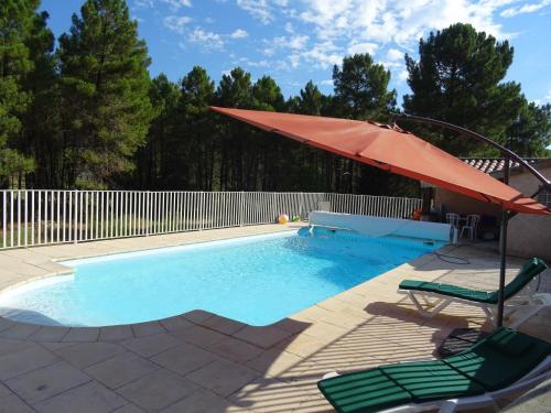 - une piscine avec un parasol rouge, des chaises et une table dans l'établissement La Journale, à Coux