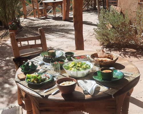 a wooden table with bowls and plates of food on it at Maison d'Hôtes Irocha in Tisselday