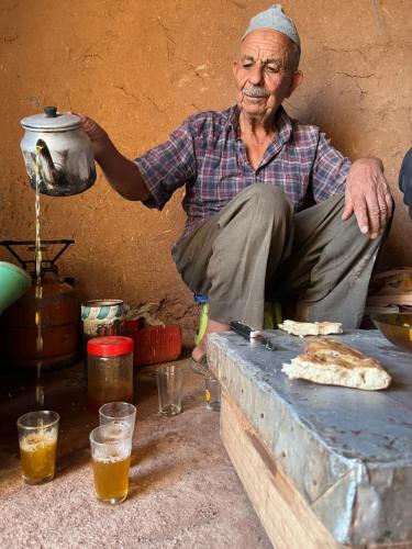 an older man sitting on a table with a pot at Maison d'Hôtes Irocha in Tisselday