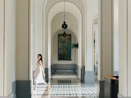 a woman walking down a hallway with a painting on the wall at Andaz Xiamen, By Hyatt in Xiamen
