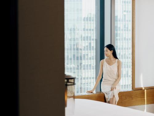 a woman in a white dress looking out of a window at Andaz Xiamen, By Hyatt in Xiamen