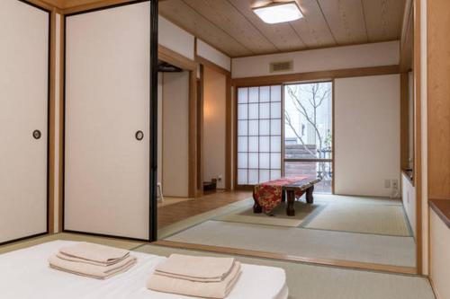 Habitación con puertas correderas de cristal y mesa con toallas. en Kiki HouseH --Self Check-in -- Room Number & Password is in the following email en Tokio