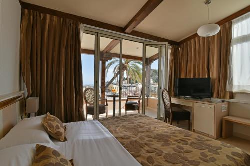um quarto de hotel com uma cama e uma secretária com uma televisão em Hotel Le Chevalier em Taormina