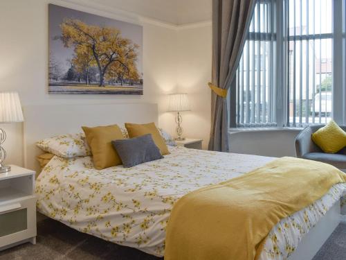 a bedroom with a bed with yellow sheets and a window at The Bungalow in Thornton