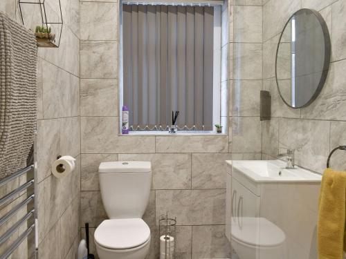 La salle de bains est pourvue de toilettes, d'un lavabo et d'un miroir. dans l'établissement The Bungalow, à Thornton