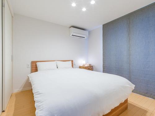 - une chambre avec un grand lit blanc et un mur bleu dans l'établissement Rakuten STAY HOUSE x WILL STYLE Itoshima 105, à Itoshima