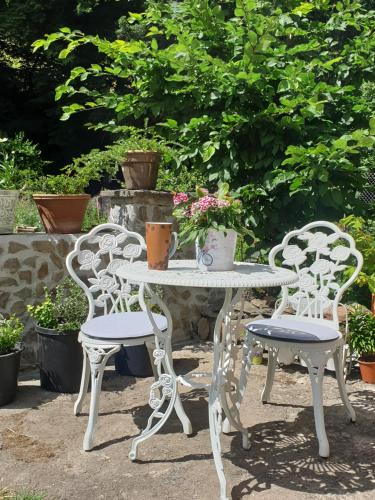 a white table and two chairs and a table with flowers at Stillvolle Designwohnung im historischen Zentrum in Stolberg i. Harz