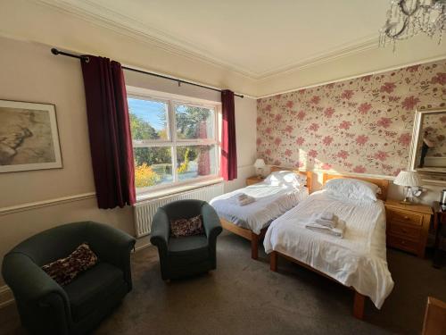 sypialnia z 2 łóżkami, krzesłem i oknem w obiekcie Melton Guest House w mieście York