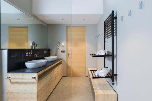 a bathroom with two sinks and a glass wall at Hotel Garberhof in Malles Venosta