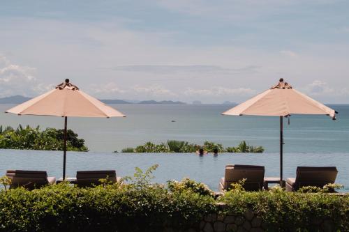 a pool with chairs and umbrellas next to the water at Amatara Welleisure Resort in Panwa Beach