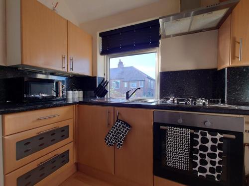 a kitchen with a stove and a sink and a window at Lovely 2 bedroom apartment located near Newcastle. in Longbenton