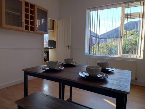 uma mesa numa sala com copos e pratos em Lovely 2 bedroom apartment located near Newcastle. em Longbenton