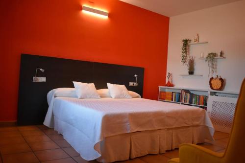 a bedroom with a white bed with an orange wall at Vivienda con piscina, gimnasio y cocina campera in Villanueva de los Infantes