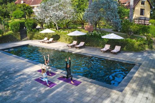 two people doing yoga in front of a swimming pool at Ana Mandara Villas Dalat Resort & Spa in Da Lat