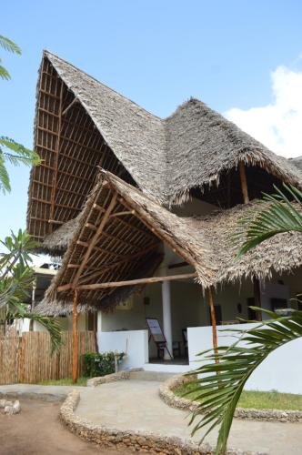a villa with a thatched roof on the beach at Pole Pole Beach House in Watamu