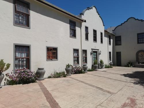 a white building with a courtyard with potted plants at Blouberg Manor in Bloubergstrand