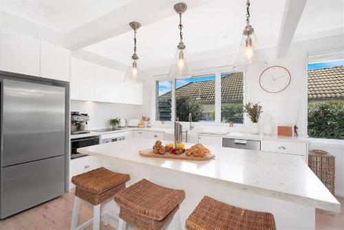 a white kitchen with a large white island with stools at 8 on Chapman in Kiama