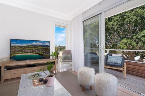 a living room with a tv and a large window at 8 on Chapman in Kiama