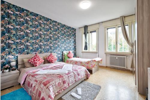 a bedroom with two beds and a floral wallpaper at R&R Apartment in Marghera