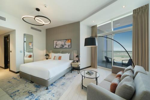 a hotel room with a bed and a couch at DAMAC Hills 2 Hotel, an Edge by Rotana Hotel in Dubai