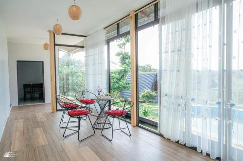 ハノイにあるNature’s House Ba Vi - Venue Travelのテーブルと椅子、大きな窓が備わる客室です。