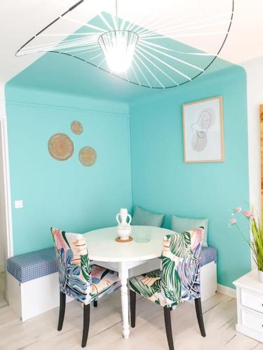 une table et des chaises dans une pièce dotée d'un mur bleu dans l'établissement Cosy Summer 2CH - Parc Expo - 2 Balcons & stationnement gratuit, à Pau