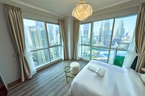 Schlafzimmer mit einem weißen Bett und großen Fenstern in der Unterkunft Magnificent Luxury 3BR with Amazing Burj & Fountain view in Dubai