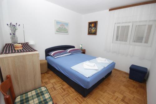 a small bedroom with a blue bed and a window at Apartment Vesna in Premantura