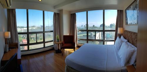 a hotel room with a bed and large windows at One Tagaytay Place Private Residences in Tagaytay