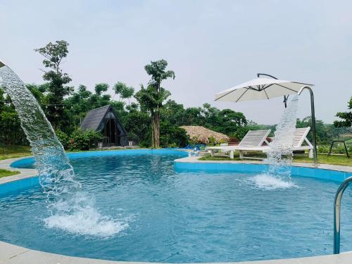 ハノイにあるNature’s House Ba Vi - Venue Travelのプールの噴水(椅子2脚、パラソル付)