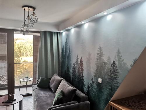 a living room with a large painting of trees on the wall at Borovi30 in Divčibare