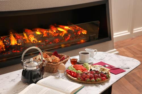 una mesa con una bandeja de comida y una chimenea en Gatto Suites&Residence en Estambul