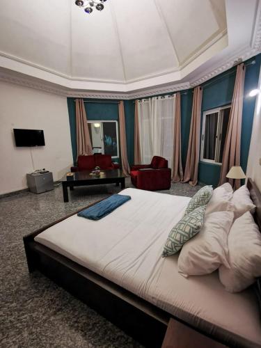 a bedroom with a large bed and a living room at L'Address in Cotonou